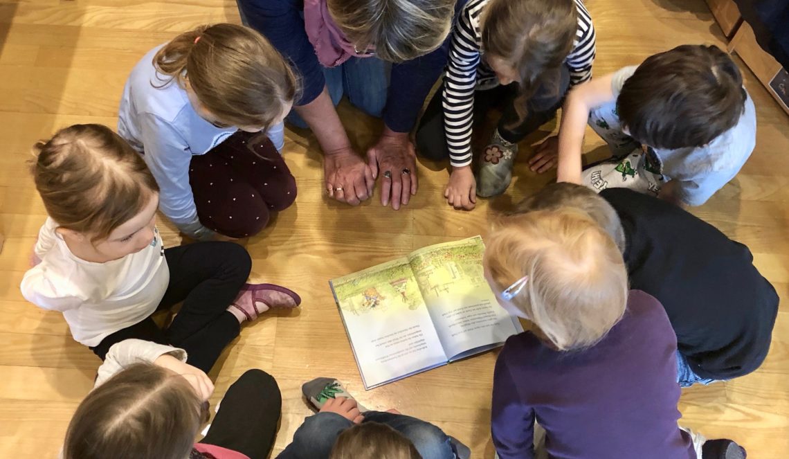 Die Kinder sitzen im Kreis um das Buch.