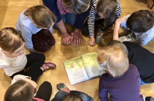 Die Kinder sitzen im Kreis um das Buch.
